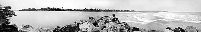 A boy watches his older brother cast a fishing net.